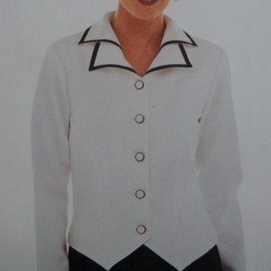 May include: A white long-sleeved blazer featuring a notched collar with black trim. The garment has a front button closure with five circular buttons that have a white center and a black border, matching the collar detail.