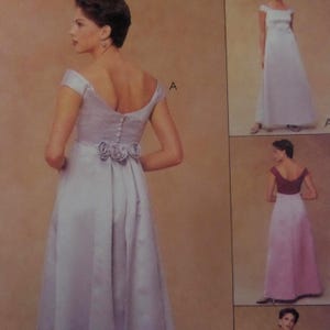 May include: A light purple off-the-shoulder formal dress with a pleated skirt and a floral embellishment at the waist. The dress has a button-up back and short sleeves. The image also shows two other dresses with similar designs.