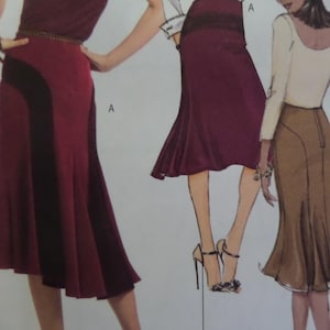 May include: A sewing pattern illustration featuring three skirt designs labeled A. One skirt is deep burgundy with a black side panel, another is a solid deep burgundy flared skirt, and the third is a tan skirt with a back zipper and flared hem.