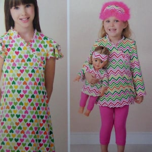 May include: A dress with a white background and a multi-colored heart pattern, alongside a matching long-sleeve top, pink leggings, and a pink fuzzy headband for a child and a doll, both featuring a multi-colored chevron pattern design.