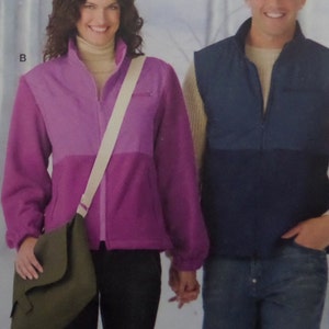 May include: A two-tone purple fleece jacket with a high collar, full-length zipper, and long sleeves with elastic cuffs, paired with a dark olive green crossbody bag featuring a wide beige strap and a flap closure, labeled with the letter B.