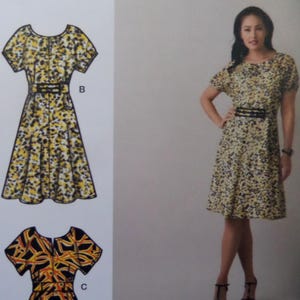 May include: A sewing pattern illustration featuring a dress with a round neckline, short sleeves, and a waist belt labeled B, alongside a photograph of the same dress in a yellow, black, and white abstract print, plus a partial view of pattern C.
