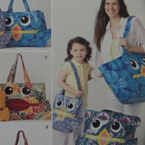May include: Various owl-themed tote bags and shoulder bags in different sizes and patterns. The bags feature large, cartoonish owl faces with big eyes, beaks, and colorful patterns. One bag is held by a woman, and another is carried by a child.