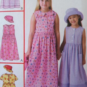 May include: A sewing pattern illustration featuring two sleeveless dresses and matching hats. One dress is pink with a multi-colored floral print, and the other is a light purple gingham check. Both dresses have buttons and pockets.