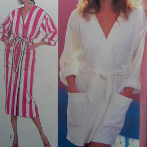 May include: Two robes are shown. One is white with a wrap-around design and pockets. The other is a pink and white striped robe with a matching belt and pockets. Both robes have long sleeves and a V-neck.