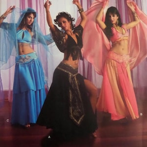 May include: Three belly dance costumes in shades of blue, black, and pink. The costumes feature flowing skirts, embellished tops, and veils. The dancers are in motion, holding up fabric. The costumes are designed for dance performances.