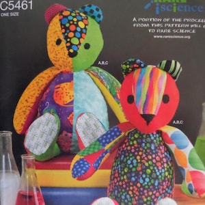 May include: Two colorful patchwork teddy bears. One bear has a red head and rainbow stripes, the other has a green head and a mix of patterns. The bears are made of fabric and have black button eyes. The text "C5461 ONE SIZE" is visible.
