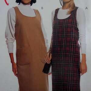 May include: Two sleeveless jumper dresses worn over white long-sleeve shirts. One dress is solid tan with two front patch pockets, labeled B. The other dress is a dark red and black plaid pattern, labeled A. Both feature a scoop neckline.