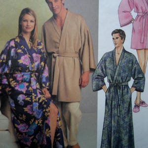 May include: A sewing pattern illustration featuring three robe styles: a long dark blue robe with a purple and yellow floral print, a solid tan knee-length robe with matching pants, and a long blue and green paisley print robe with a tie waist.