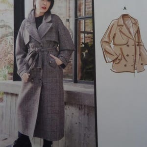 May include: A long, grey plaid coat with a wide collar, long sleeves, and a matching fabric tie belt at the waist. Beside it is a technical line drawing labeled A, showing a shorter, double-breasted jacket with a collar and pockets.