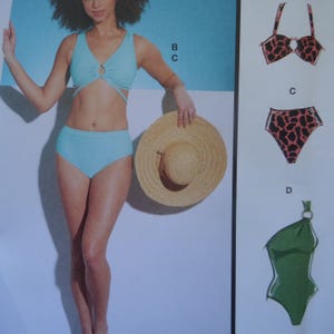 May include: A light blue two-piece swimsuit with a V-neck top featuring a center ring detail and high-waisted bottoms. Additional illustrations show a leopard print bikini top and bottoms labeled B and C, and a green one-piece swimsuit labeled D.