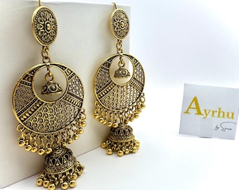 Könnte beinhalten: Ein Paar goldfarbene Ohrringe mit aufwendigen Filigranmustern. Jeder Ohrring hat ein kreisförmiges Design mit einem kleineren glockenförmigen Anhänger und hängenden Perlen. Die Ohrringe haben einen Hakenverschluss.