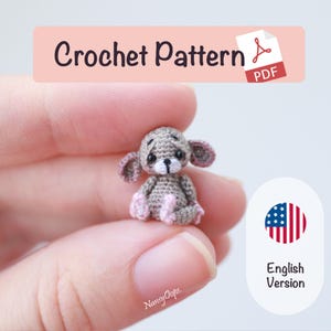 May include: A miniature crocheted mouse in shades of grey and pink is held up. The image features the text "Crochet Pattern PDF" and "English Version". The mouse is a handmade item.