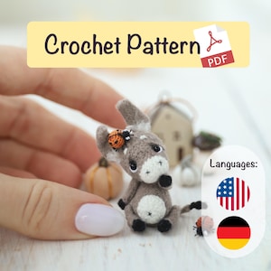Könnte beinhalten: Gehäkeltes Esel-Figürchen, überwiegend grau und weiß, mit einem Marienkäfer-Detail. Das Bild zeigt den Text "Crochet Pattern PDF". Der Esel ist ein Miniatur-Bastelartikel.