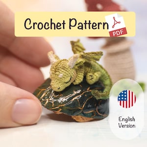 May include: A crocheted green and yellow dragon figurine resting on a dark green, textured surface. The dragon has closed eyes, and the image includes text that says "Crochet Pattern PDF" and "English Version".