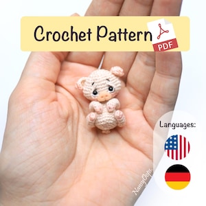 May include: A small, crocheted piglet in shades of pink and cream, held in a hand. The piglet has a sad expression and is labeled as a "Crochet Pattern PDF". The image also includes the flags of the United States and Germany.