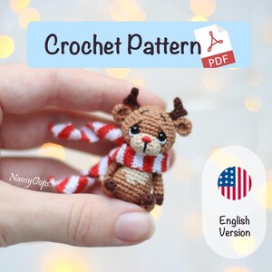Puede incluir: Un reno de ganchillo con una bufanda a rayas rojas y blancas. El reno tiene cuernos marrones y una nariz roja. La imagen incluye el texto "Crochet Pattern PDF" y "English Version".