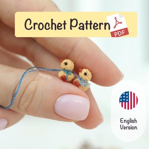 以下が含まれることがあります： 青いリボンと赤い足を持つ、2匹の小さなかぎ針編みのヒヨコが青い糸で繋がれています。画像には「Crochet Pattern PDF」と「English Version」の文字が含まれています。