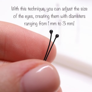 May include: Close-up of two black-headed pins with the text: "With this technique, you can adjust the size of the eyes, creating them with diameters ranging from 1 mm to 3 mm!" These pins are likely used for crafting or doll making.