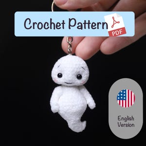May include: A handmade white crochet ghost keychain with black eyes and a small smile. The keychain is attached to a metal ring. The image includes a light blue banner that says "Crochet Pattern PDF".