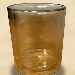 Op de afbeelding: Een heldere, amberkleurige glazen tumbler met een afgeronde basis en rechte zijkanten. Het glas heeft een gladde, gepolijste afwerking en is ontworpen om vloeistoffen in te bewaren. De tumbler is ongeveer 10 cm hoog.