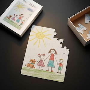 May include: A white jigsaw puzzle with a drawing of a family and a dog. The puzzle is partially assembled, with the box and some pieces visible. The drawing features a yellow sun, green grass, and a family of four.