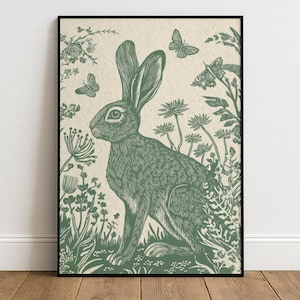 Könnte beinhalten: Gerahmter Kunstdruck mit einer detaillierten Illustration eines Hasen in einem Feld mit Blumen und Schmetterlingen. Das Kunstwerk ist in Grüntönen auf cremefarbenem Hintergrund gehalten und hat eine Vintage-Ästhetik. Der Druck ist in einem schwarzen Rahmen.