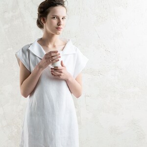 May include: A white linen dress with a wide collar and short sleeves. The dress is knee-length and has a relaxed fit.