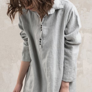 May include: A long-sleeved, light grey linen shirt dress with a button-up front and a collared neckline.