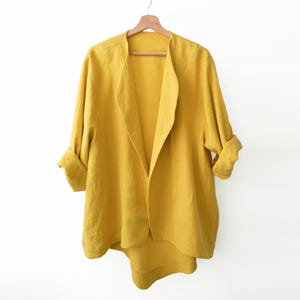 May include: A yellow linen jacket with a long, open front and rolled-up sleeves.