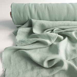 Peut inclure: Un rouleau de tissu en lin vert clair. Le tissu est drapé et plié, montrant la texture et le tissage naturel. Les bords du tissu sont inachevés, ajoutant à l'esthétique rustique. La couleur est un vert pastel.