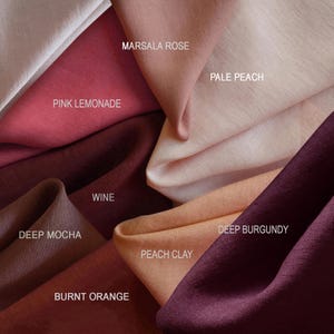 May include: A collection of folded fabric swatches in various colors labeled Marsala Rose, Pale Peach, Pink Lemonade, Wine, Deep Mocha, Deep Burgundy, Peach Clay, and Burnt Orange. The textile has a visible weave and soft, draped folds.