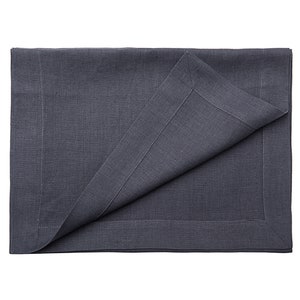 May include: A dark gray linen placemat with a stitched border. The placemat is folded in half, showing the underside.