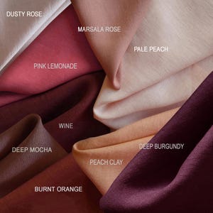 May include: A close-up of fabric swatches in various shades of pink, red, and brown. Colors include Dusty Rose, Marsala Rose, Pink Lemonade, Wine, Pale Peach, Deep Burgundy, Deep Mocha, Peach Clay, and Burnt Orange. The names of the colors are printed on the fabric.