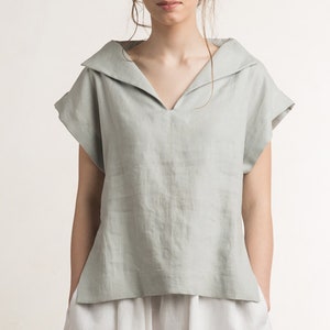 May include: A light green linen top with a wide, folded collar and short sleeves.