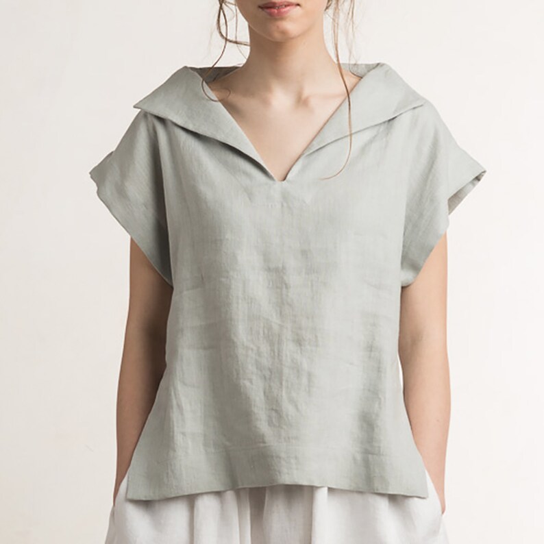 May include: A light green linen top with a wide, folded collar and short sleeves.