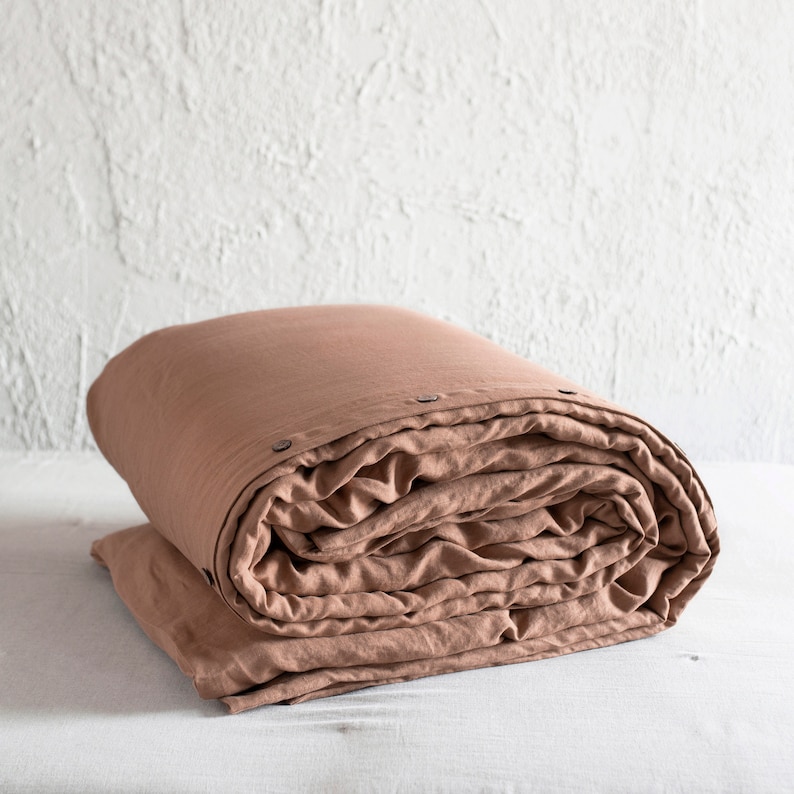 May include: A rolled up terracotta linen duvet cover with button closures.