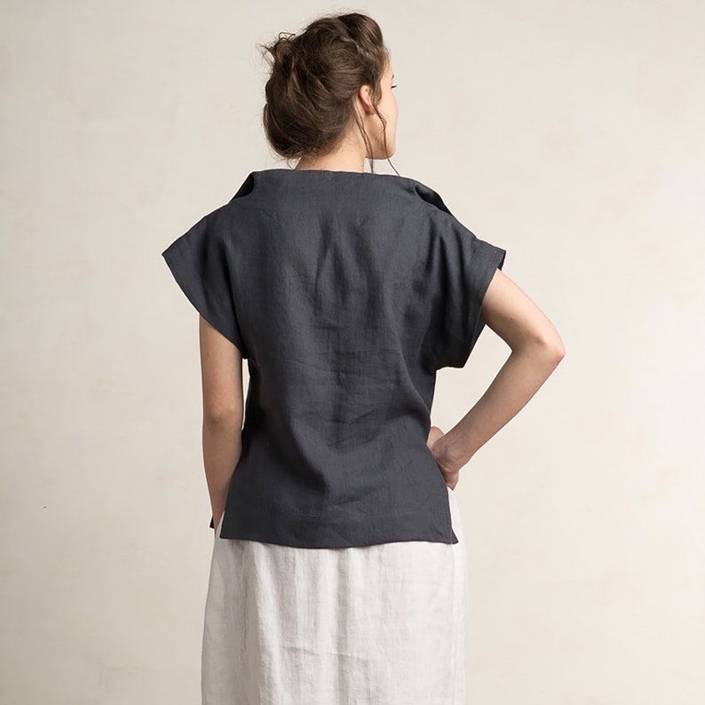 May include: A dark gray linen top with short sleeves and a relaxed fit. The top has a scoop neckline and a slightly cropped hem.