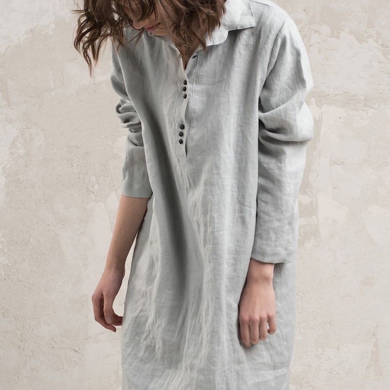 May include: A long-sleeved, light grey linen shirt dress with a button-up front and a collared neckline.