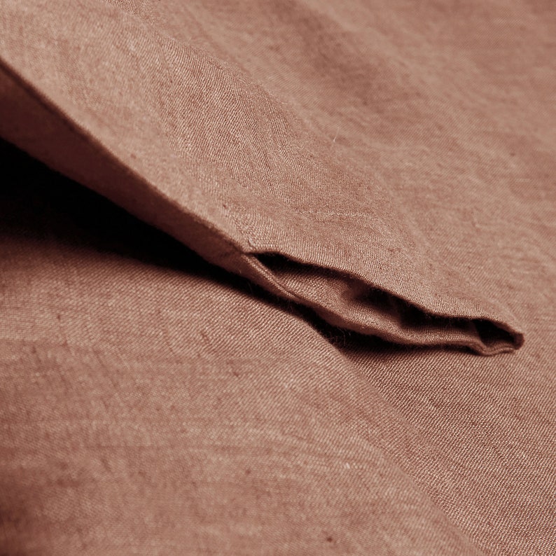 May include: Close-up of a brown linen fabric with a folded edge. The fabric has a subtle texture and a warm, earthy tone.