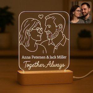 May include: A personalized LED night light featuring a couple's portrait, with the names "Anna Petersen & Jack Miller" and the phrase "Together Always" engraved. The light sits on a wooden base and is illuminated.