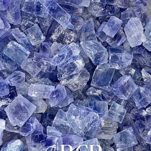 May include: A close-up shot of a collection of blue crystals. The crystals vary in size and shape, with a mix of light and dark blue hues. The image includes the text "BCR BLUE CRYSTAL ROCK INC."