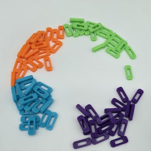 May include: An assortment of small, rectangular plastic pieces in various colors: orange, green, blue, and purple. Each piece has a rectangular opening in the center. The pieces are scattered on a white surface.