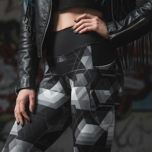 Może przedstawiać: Legginsy z geometrycznym wzorem w kolorze czarno-białym. Legginsy mają powtarzający się wzór szarych i białych kształtów geometrycznych. Modelka ma na sobie czarne buty bojowe i czarną skórzaną kurtkę z frędzlami.