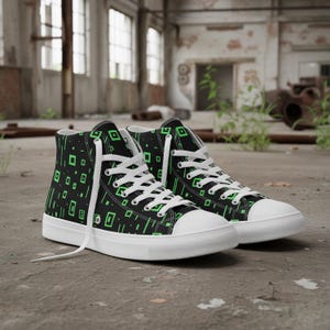May include: Black high-top sneakers with a white sole and laces. The sneakers feature a pattern of green squares and lines on the black canvas. The shoes are set against a concrete background.