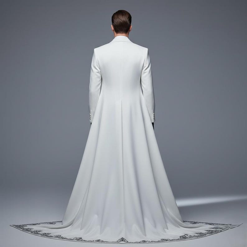 May include: A white formal coat with a long train. The coat has a tailored fit with a high collar and long sleeves. The train is decorated with a detailed, dark gray embroidered border. The person is facing away from the camera.