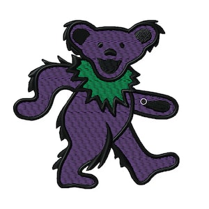 May include: Embroidered purple bear with a green collar and black outlines. The bear is smiling with its arms and legs outstretched. The design is likely for patches, apparel, or accessories. The image is on a white background.