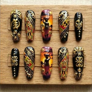 May include: A collection of ten artificial nails with intricate designs. The nails feature a variety of patterns, including geometric shapes, African-inspired motifs, and depictions of a woman carrying a basket. Colors include black, gold, red, yellow, and orange.