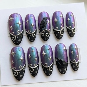 May include: A set of ten oval press-on nails featuring a gradient of purple and teal with a black base. The design includes raised silver metallic stars, swirling filigree patterns, and two black raven figures perched on the nail surfaces.