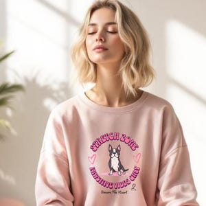 May include: A light pink sweatshirt with a circular graphic featuring a Boston Terrier dog, hearts, and the text "STRETCH ZONE, FUNSHINE VIBES ONLY, Sincere The Heart". The sweatshirt is made of a soft material.